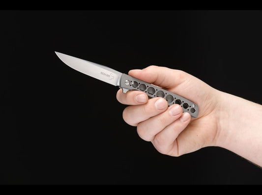 Boker Plus titanium framelock folder held in hand against black background