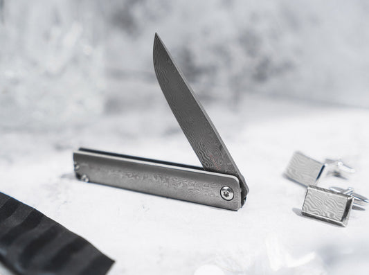 Boker Plus Gemma damascus folder open on marble with damascus cufflinks